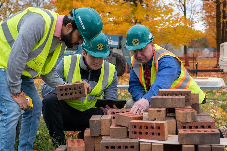 Construction Engineering Management class at Clarkson University; professor and students standing at brick pile.